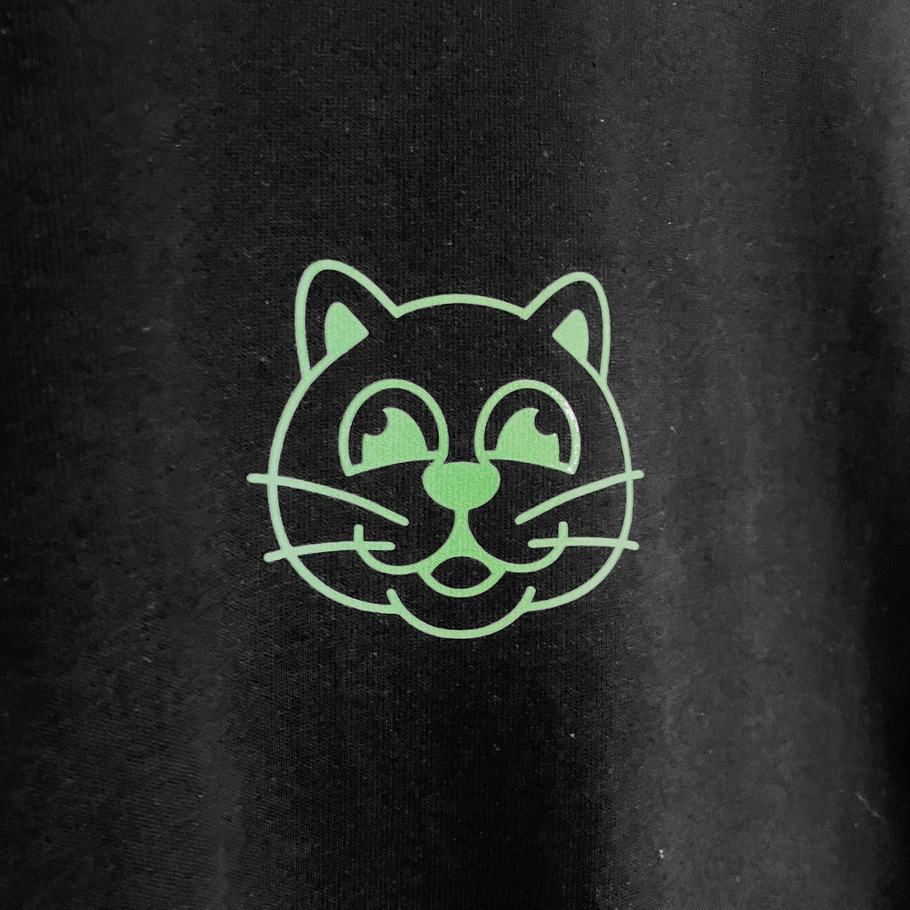 Tee-shirt noir et vert Herbe à Chat CBD HAC, en coton, avec logo CBD, porté par un mannequin, style décontracté et tendance.